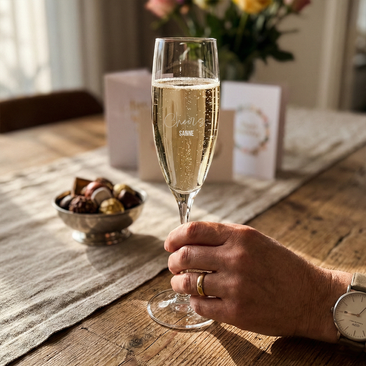 Sektglas mit Gravur „Cheers Sanne“ in der Hand Sektglas mit Gravur „Cheers Sanne“ in der Hand